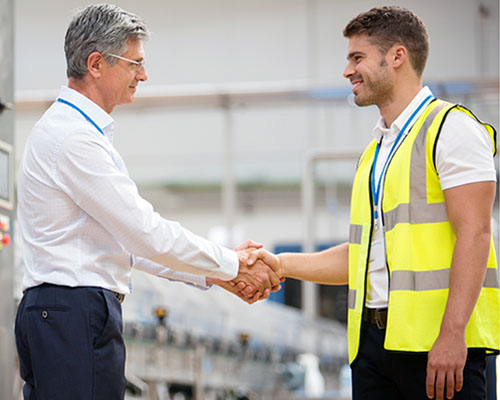 Male manager shaking hands with worker in factory